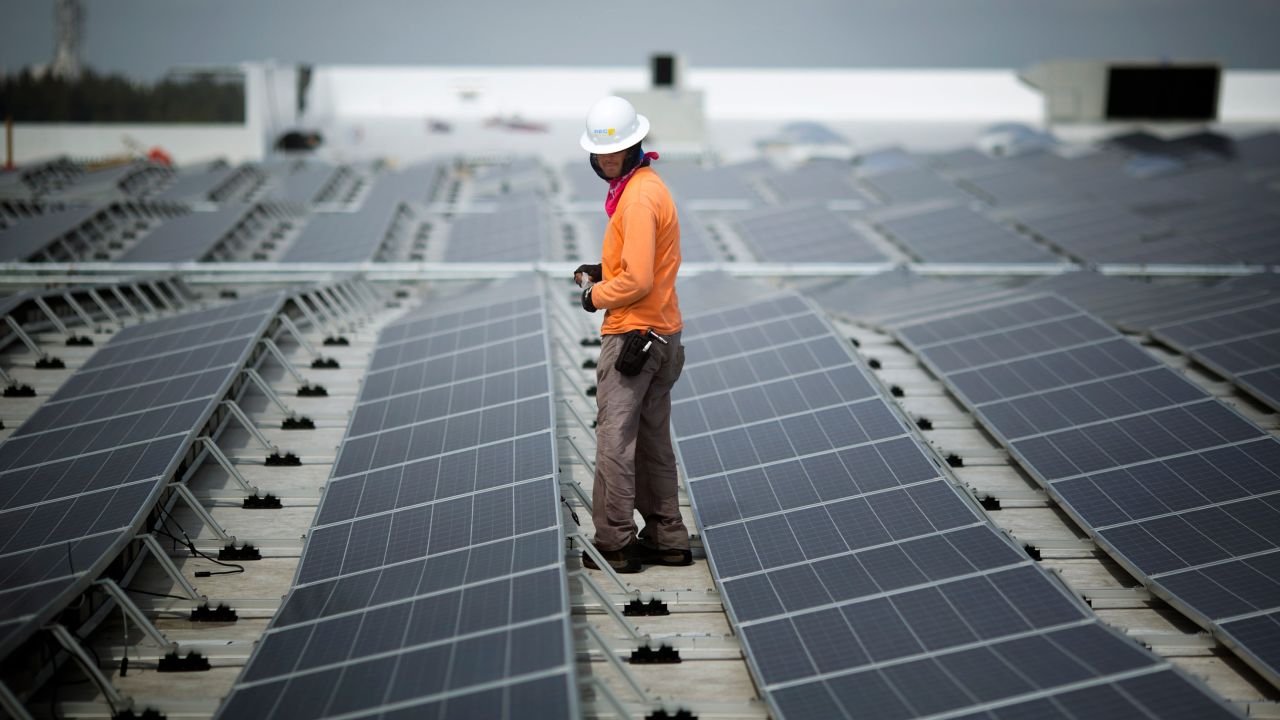 A worker walks among solar panels being installed on the roof of an IKEA in Miami in 2014. As of February, IKEA had solar installed at 90% of its US locations.